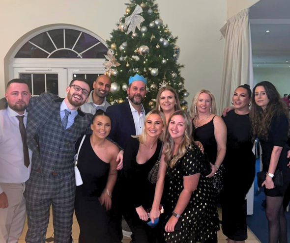 Sales department posing for a photo infront of the Christmas party's tree. 